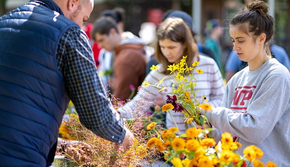 Students look at flowers at the farmers market on the Quad.