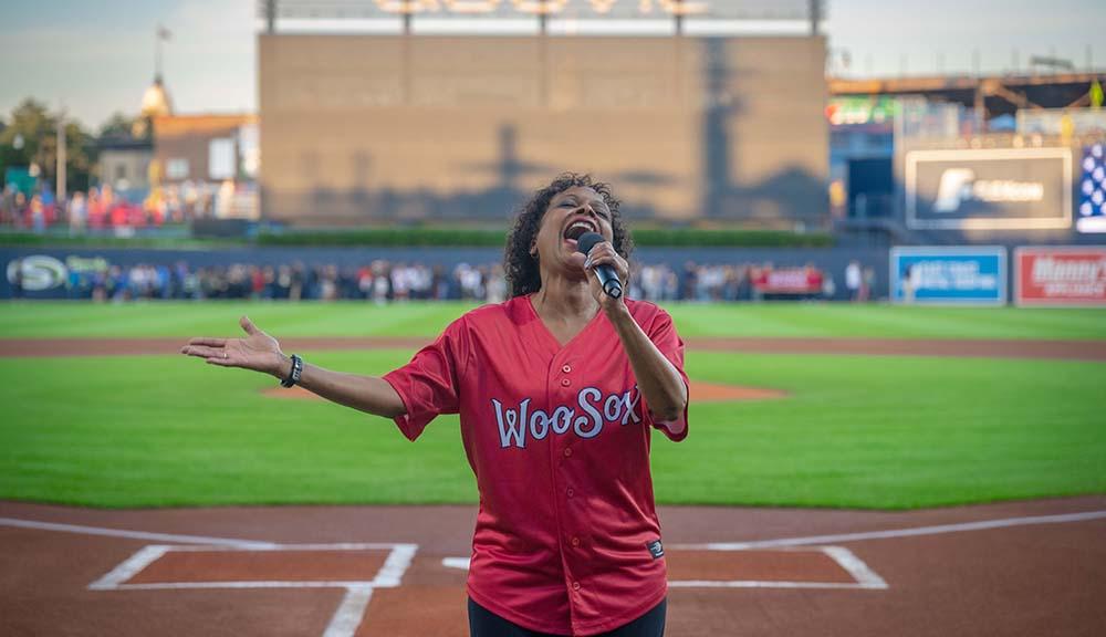 Dean of The Business School Debora Jackson sings the National Anthem at a recent WooSox game.