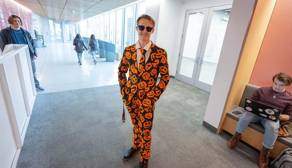 A student dresses in a suit with pumpkins on it for Halloween.