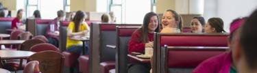 Student laughing at table with others in dining hall