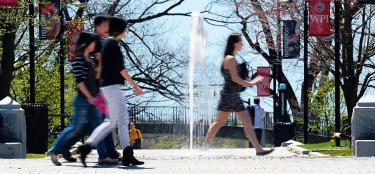 A group of students walking by the fountain at Reunion Plaza on a sunny spring day.