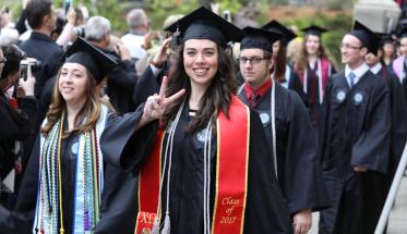 A female member of WPI's undergraduate Class of 2017 crosses the Earle Bridge and gives the victory sign