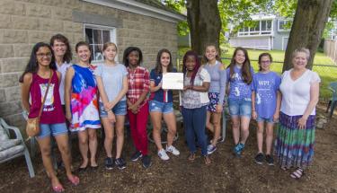 Nine young girls from Camp Reach, Joanne Alley, and Chrysanthe Demetry pose with a certificate.