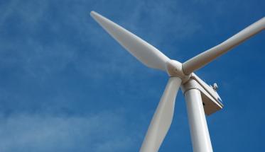 A close-up of a wind turbine against a blue sky.