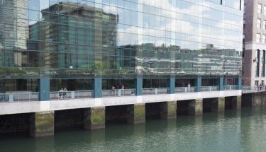 An exterior shot of WPI Seaport, which is made up of floor-to-ceiling glass windows, and is in front of a body of water.