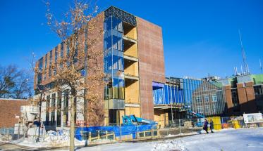 A shot of the Foisie Innovation Studio & Messenger Residence Hall under construction, with a blue sky behind it.