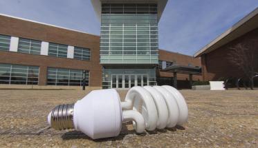 A photo of an energy-saving lightbulb on the ground in front of the Sports & Recreation Center.