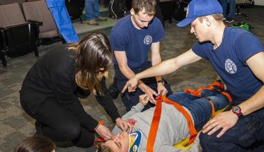 Students from the EMS squad practice techniques on safely securing someone to a stretcher.