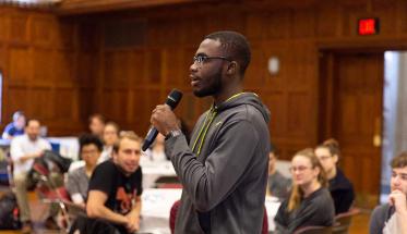 A student holding a microphone participates in the first annual Social Justice Summit on campus.