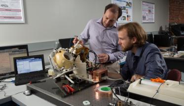 Gregory Fischer, left, and research scientist Christopher Nycz examine a prototype of the MRI-compatible robotic system developed in the first phase of the NIH-funded research program.