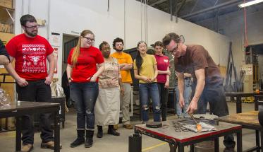 WinterSession participants watch as a member of the Worcester Center for Crafts gives a lesson in glassblowing.