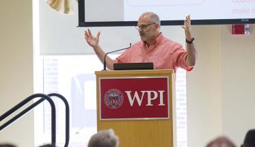 Randy Bass stands at a WPI podium and addresses attendees of the Institute on Project-Based Learning.