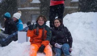 Students smile and wave on Boynton Hill during a snowstorm.