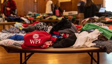 Clothes are folded on a table, with a red WPI sweatshirt in the middle.