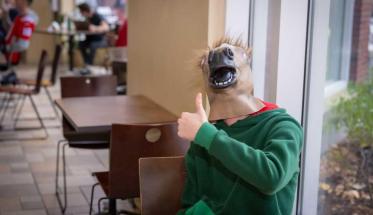 A person in a floppy horse mask giving the camera a big thumbs up