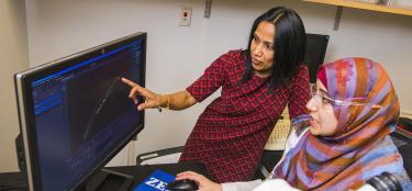 WPI professor working with a student visualizing data on a computer screen.