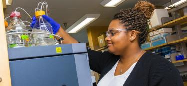Female graduate student reaches for a beaker in a WPI lab