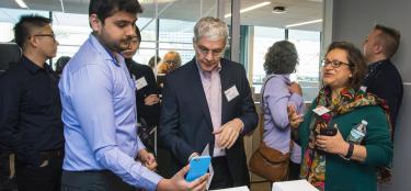Professor Soussan Djamasbi and user experience conference attendees look at mockups; one with an iPhone