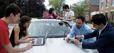A team of students and professors installing specialized antennas on a car