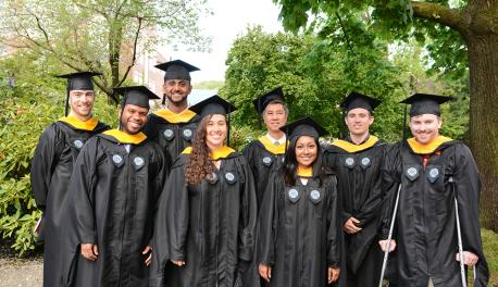 A group of graduate students take a photo together in their graduation robes following Commencement.