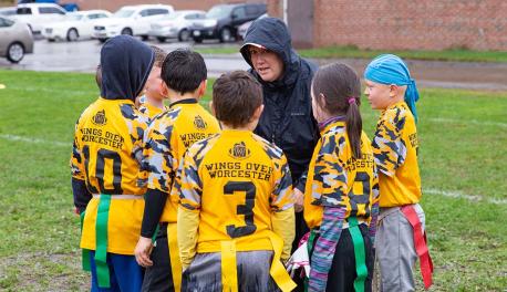Sustain Roberts huddles with her daughter's flag football team during a game.