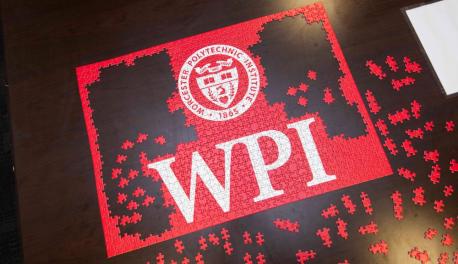An aerial photo of a red WPI puzzle in the process of being completed.