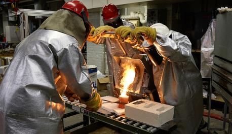WPI researchers pour molten metal into a preheated investment casting mold.