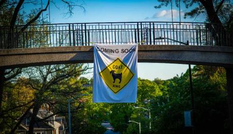 A photo of a banner hanging on Earle Bridge that reads "Coming Soon: Goat X-ing"