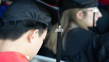 A close-up photo of a student in commencement regalia, including a 2023 charm.
