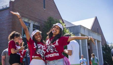 Students in red WPI Superfan shirts smile for a photo during a sunny day on the Quad.