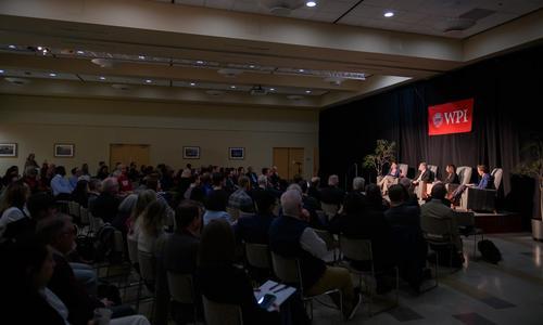 WPI President Grace Wang and three expert panelists sit in front of a packed audience while discussing A.I. and the future of work