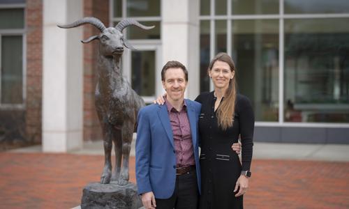 Steve Vassallo and his wife, Trae, stand outside in front of a bronze goat statue symbolizing Gompei, the WPI mascot.