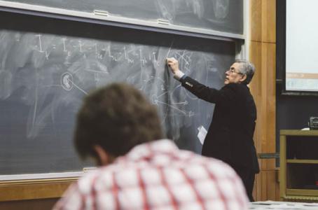 Student at lecture while professor writes on chalkboard