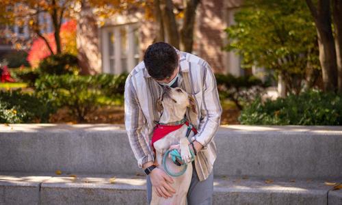 Jordan Rosenfeld holds up Cleo and they look at each other near the fountain on campus.