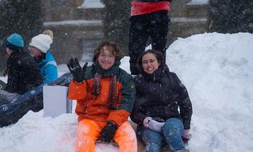 Students smile and wave on Boynton Hill during a snowstorm.