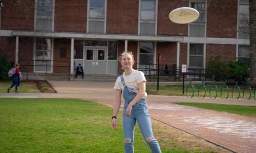 A student gets ready to catch a frisbee on the Quad.