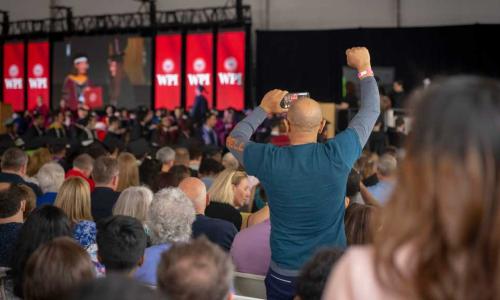 A family member takes a photo of a graduate while raising a fist in the air.