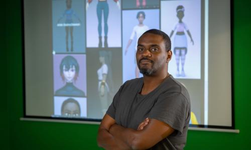 IMGD Associate Professor of Teaching Farley Chery stands in front of rigs of color images.