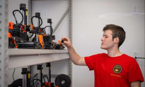 A student observes the XRP robots on a shelf. alt